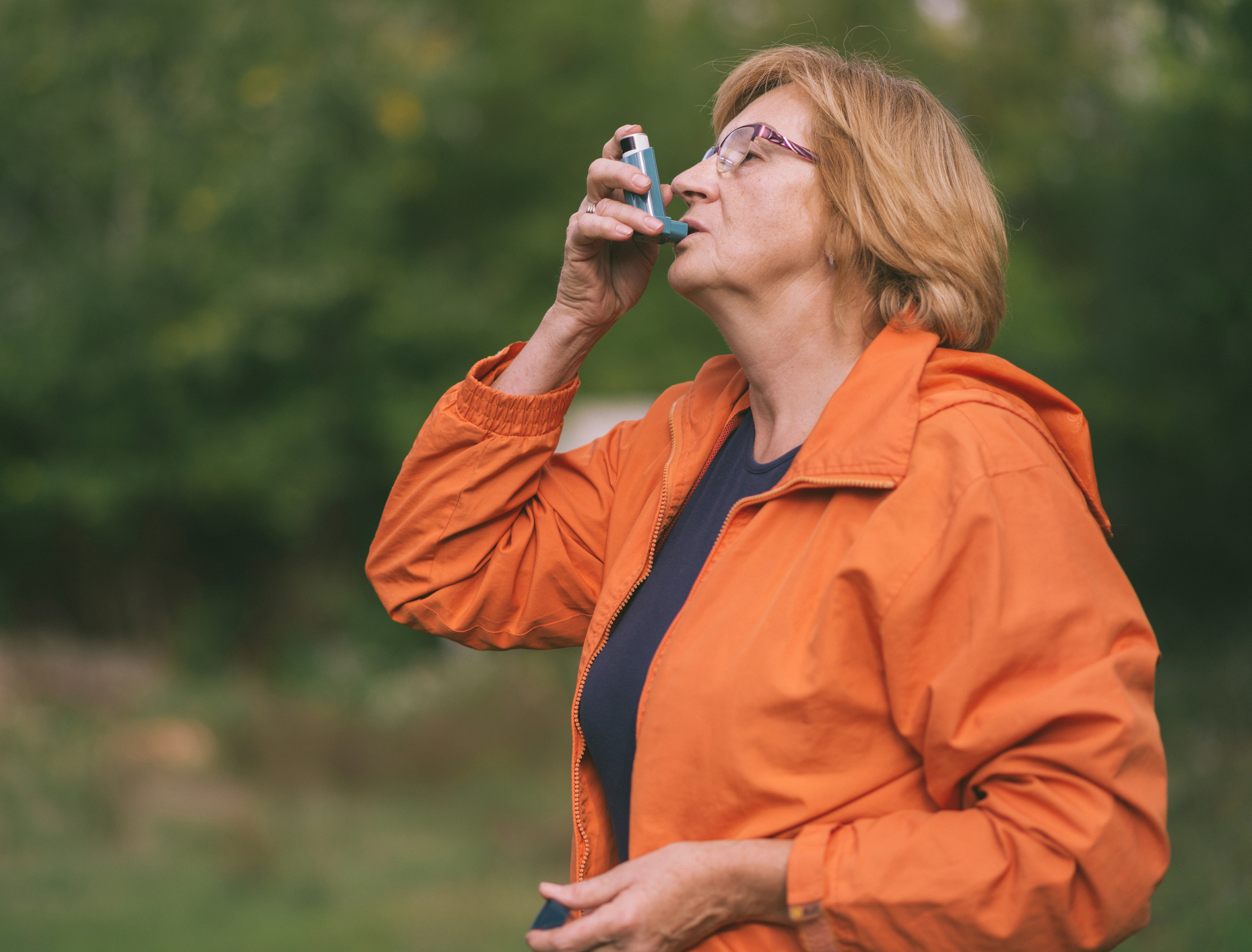 Woman outdoors using an inhaler