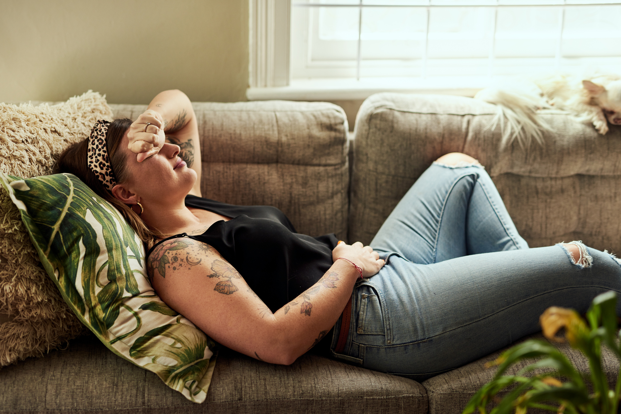 Woman lying on sofa holding her stomach Woman lying on sofa holding her stomach