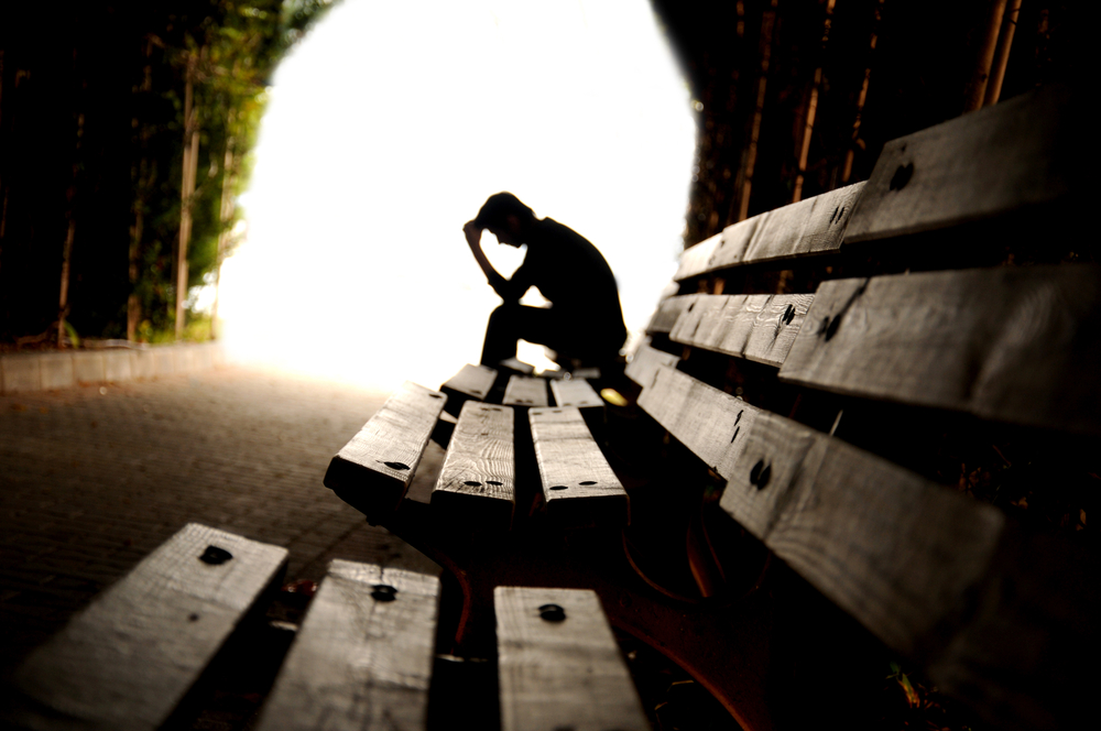 Person with head in hands on a deserted bench