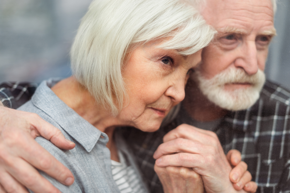 Senior man and woman holding hands and leaning close to each other