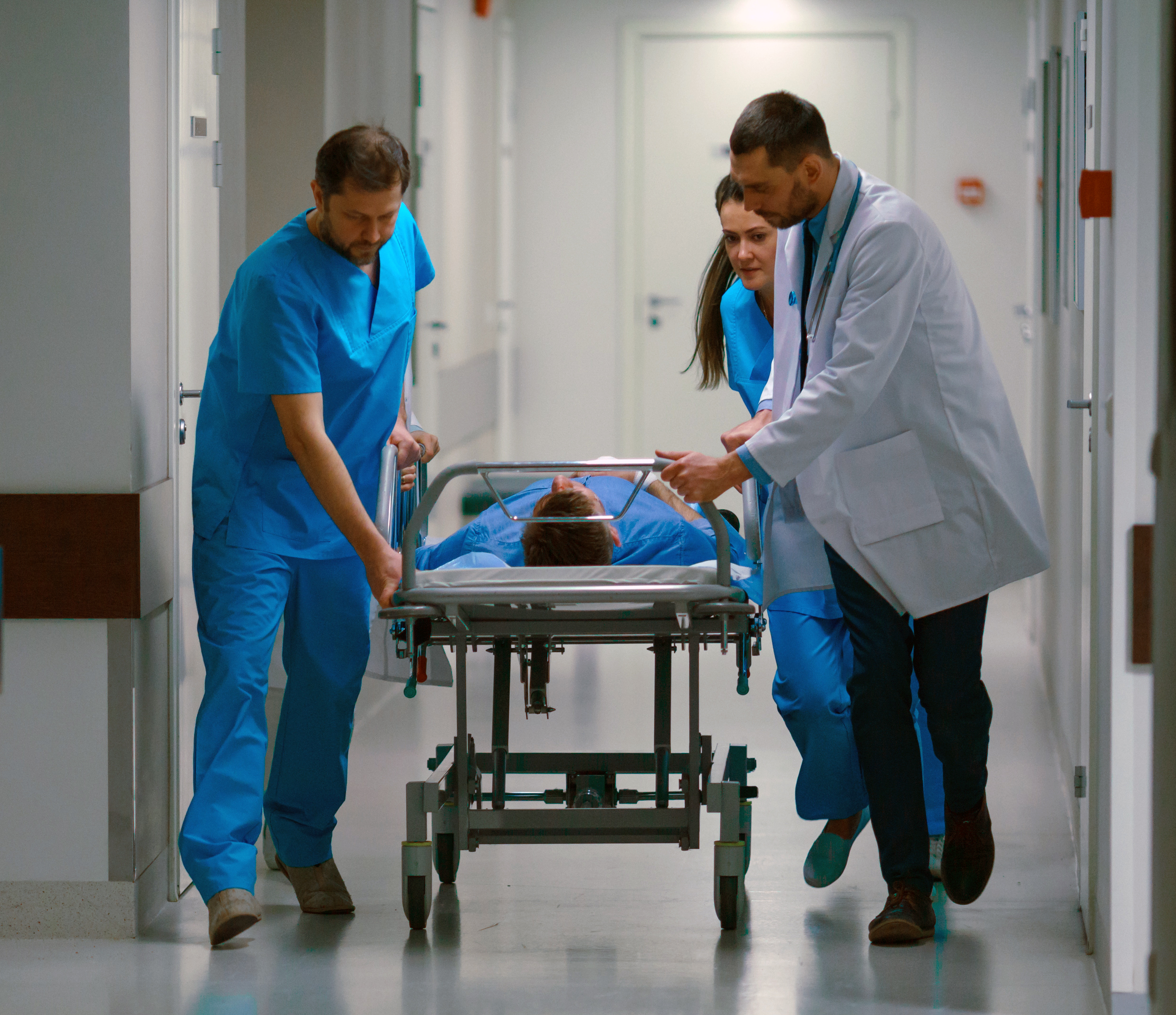 Emergency workers pushing a patient down a hospital corridor.