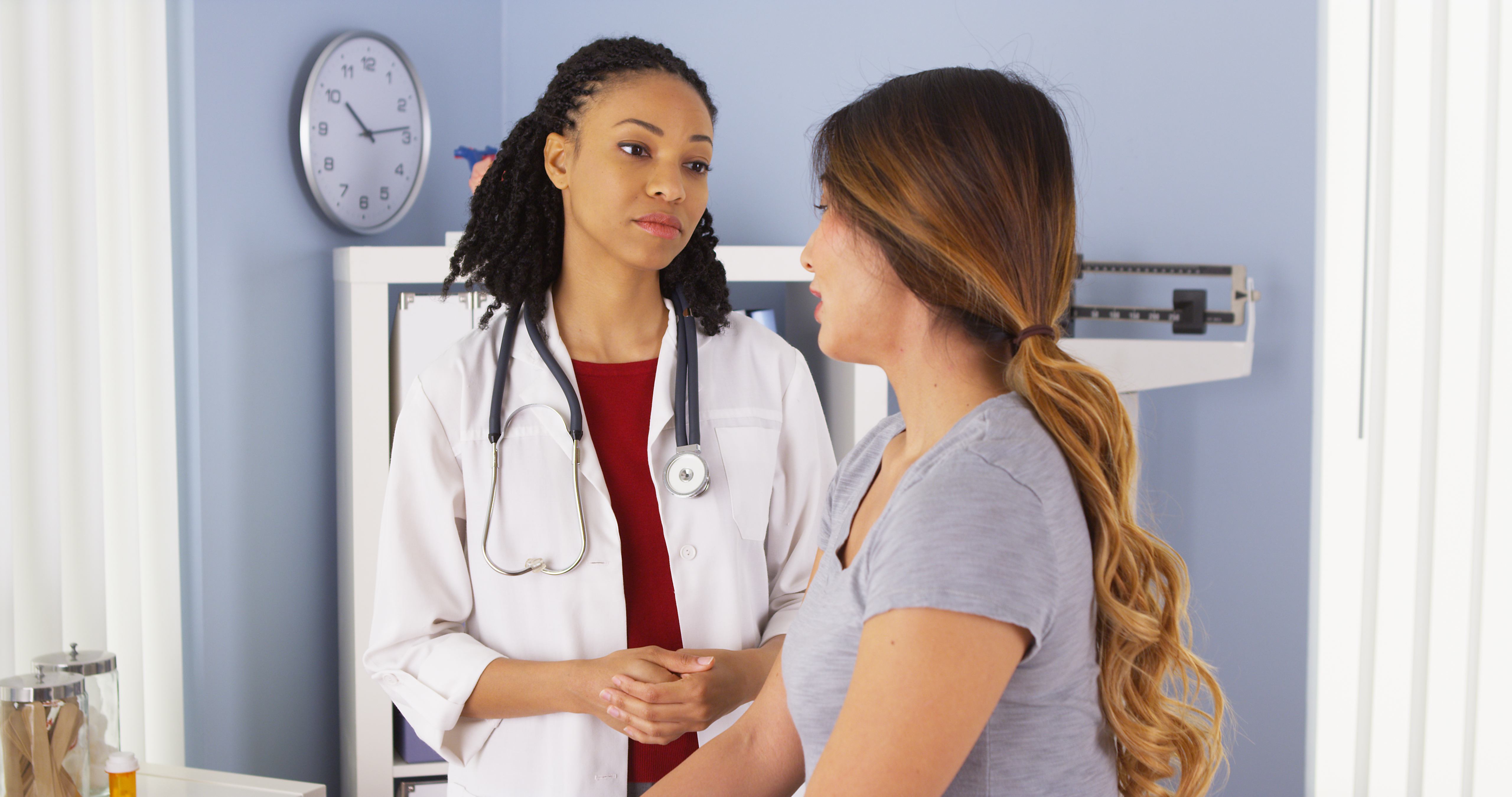 Doctor talking to young female patient in exam room. Doctor talking to young female patient in exam room.