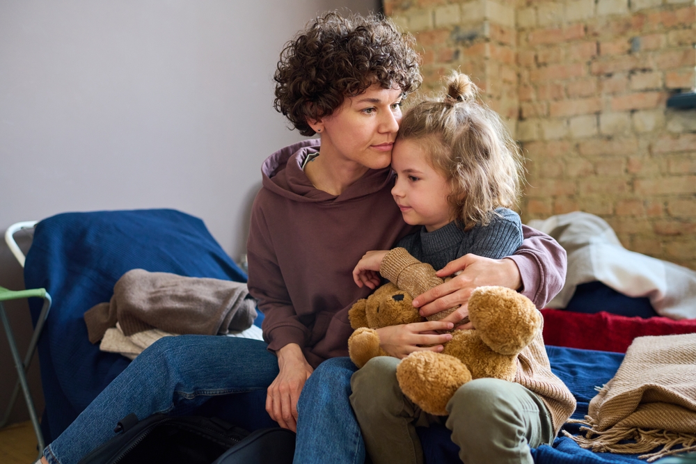 Young woman comforting boy on a cot. Young woman comforting boy on a cot.