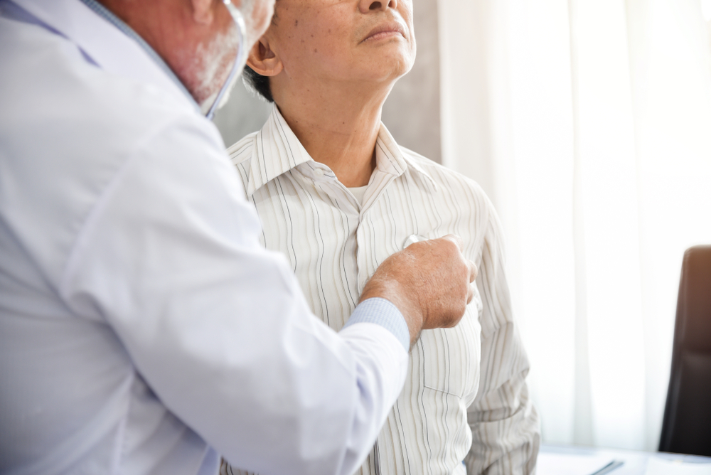 Doctor listening to older patient’s chest with stethoscope.