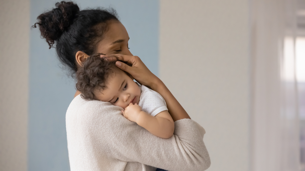 Mother holding infant against chest.