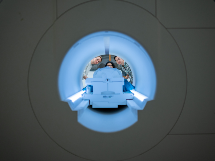View through an fMRI scanner as three researchers peer inside.