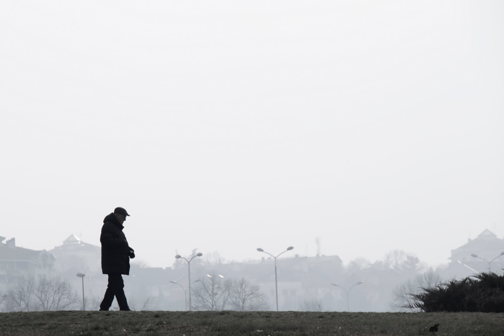 Silhouette of elderly man walking alone outside a city on a hazy, polluted day. Silhouette of elderly man walking alone outside a city on a hazy, polluted day.