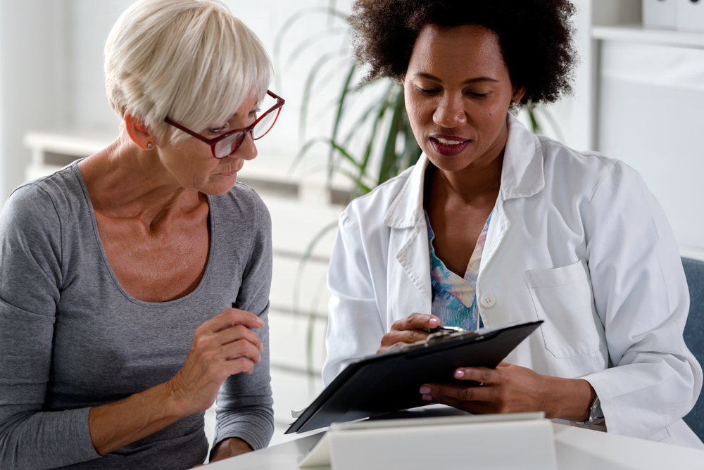 Female doctor speaking with an elderly female patient while looking at test results. Female doctor speaking with an elderly female patient while looking at test results.