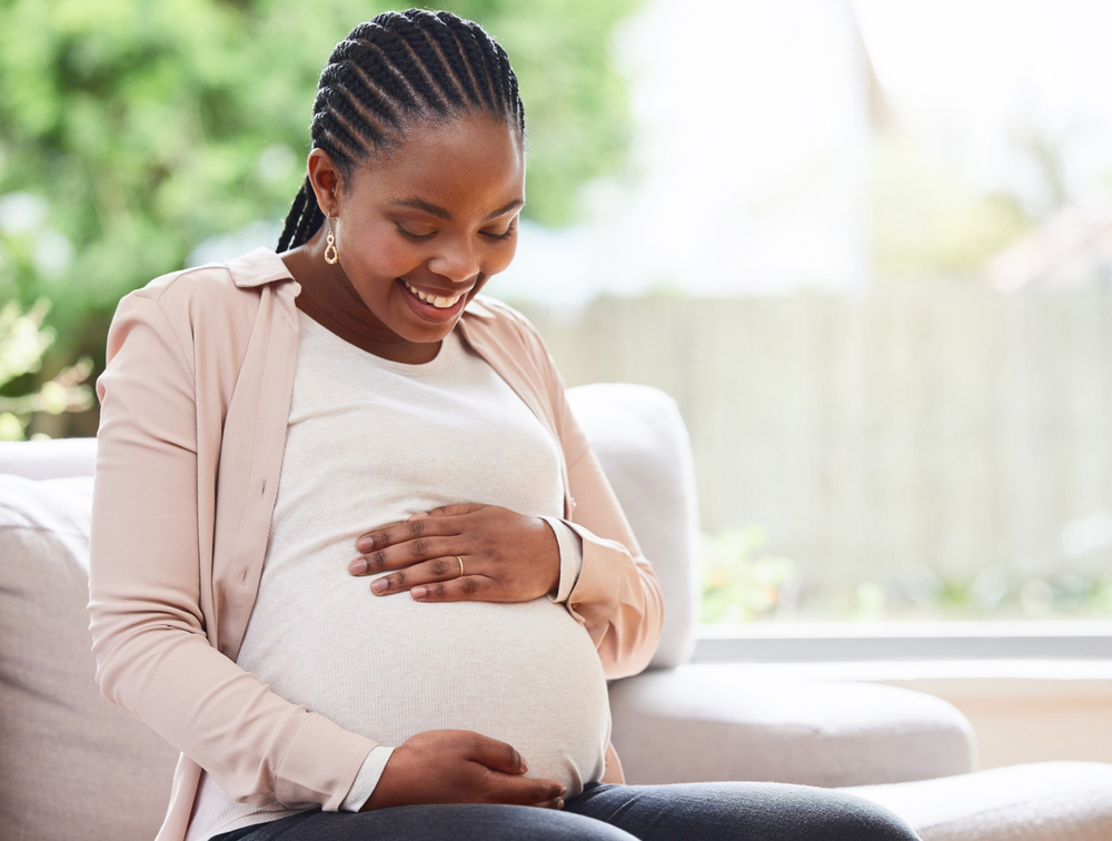 Pregnant woman on sofa smiling down at her belly.