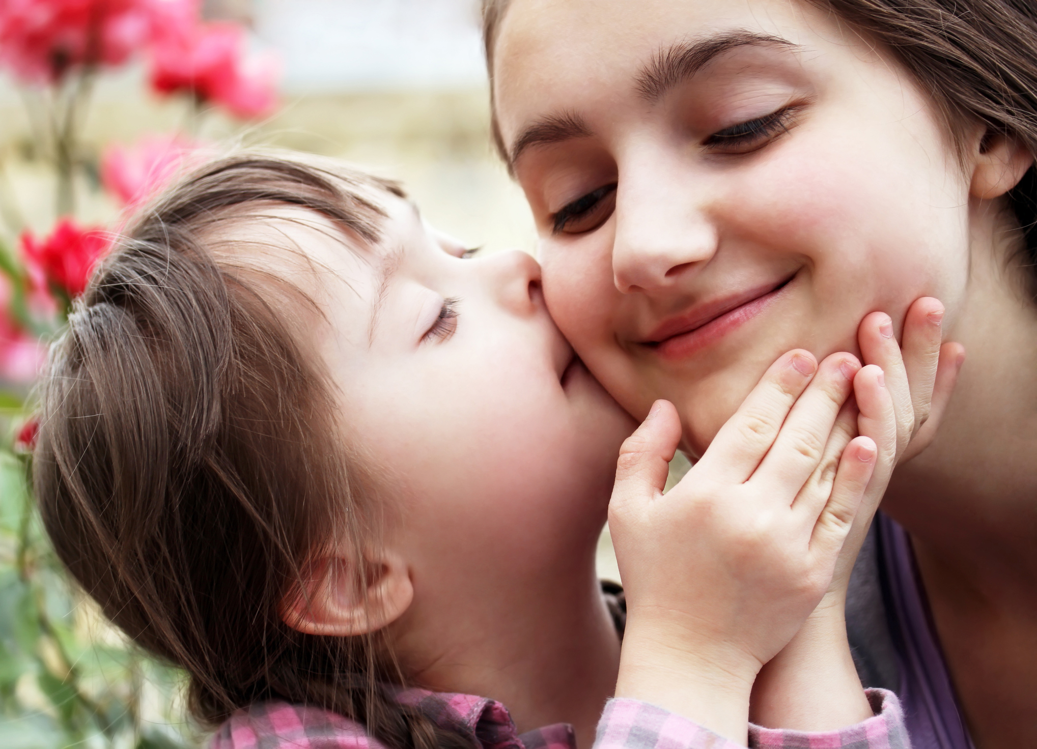 Child with Down Syndrome kissing the cheek of an adult.