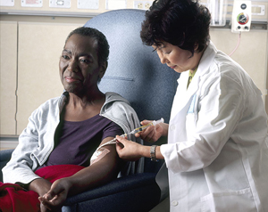 A nurse administering chemotherapy a woman through a catheter.