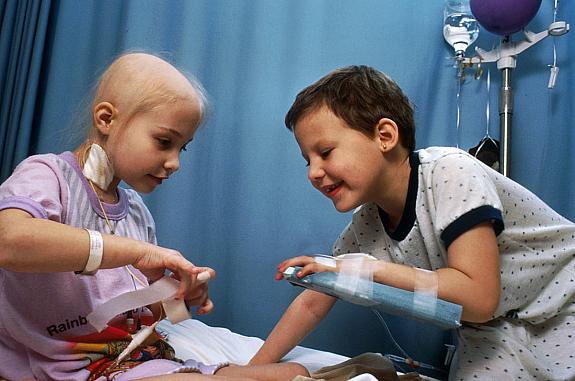 Two young girls with acute lymphocytic leukemia receiving chemotherapy. The girl on the left has an IV tube in the neck, the other girl's IV is in her arm.