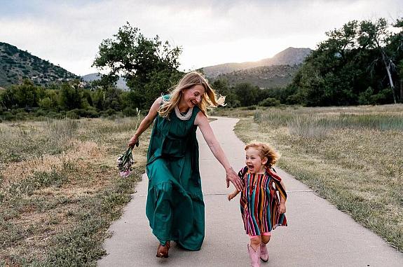 Mother and daughter running through a meadow and laughing.
