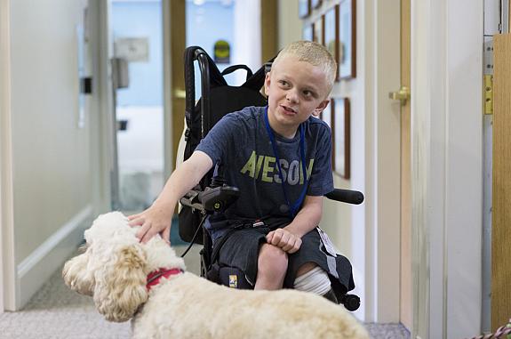 9 year old who received treatment for neurofibromatosis type 1 (NF1) in a phase II clinical trial run by NCI is petting a dog.
