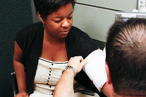 A male nurse puts a blood pressure cuff on a woman's left arm.