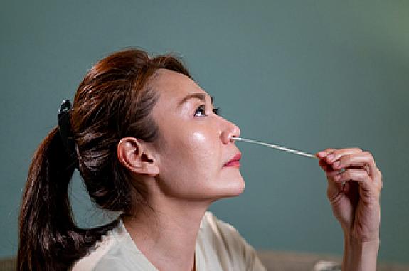 Woman swabs her own nose for an at-home COVID-19 test.