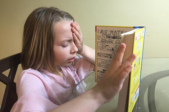 Child is reading a book with one eye covered as part of clinical trial.