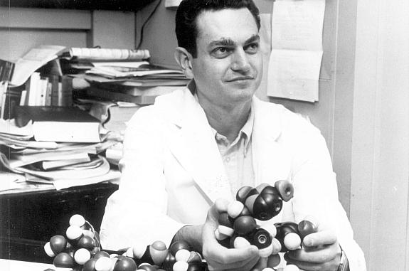 Dr. Marshall Nirenberg sitting at desk holding DNA models, ca. 1960s. Nirenberg shared the Nobel Prize in Physiology or Medicine in 1968 for discovering the key to deciphering the genetic code.