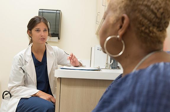 A female health care provider in a white lab coat and female patient consult.