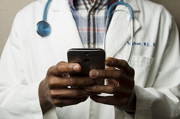 Person wearing a lab coat holding a cellphone.