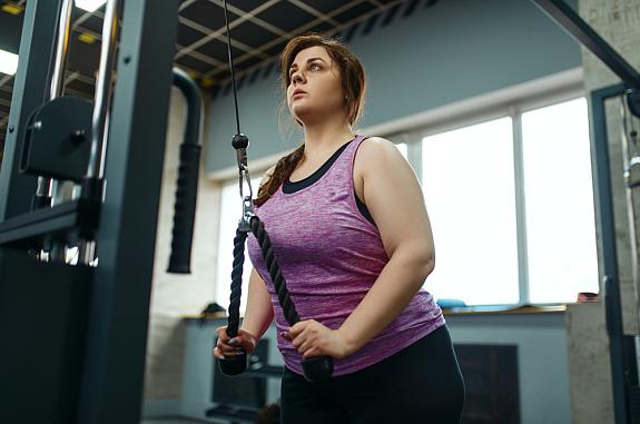 Overweight woman doing weight exercise in gym