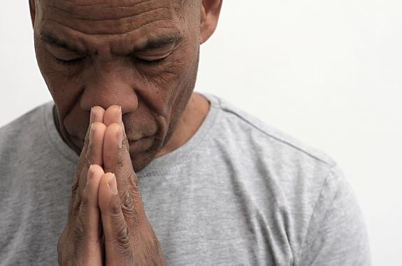 Black man with hands together in thought or prayer