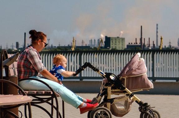 Woman with baby sitting on a bench in a polluted city