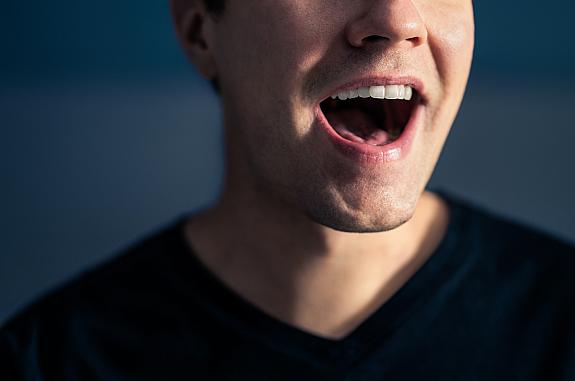 Close-up photo of the mouth of a man singing.