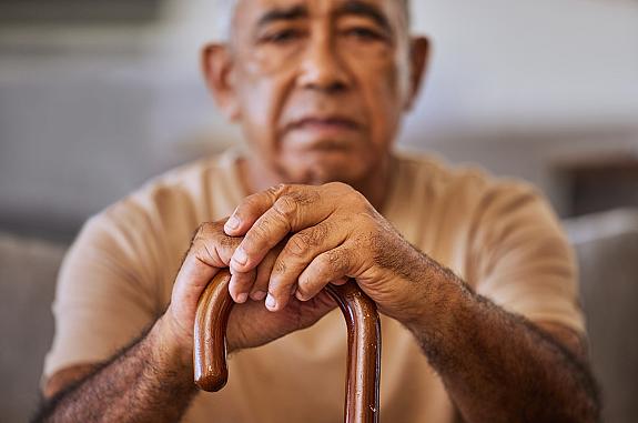 Portrait of a senior man with his hands on a cane.
