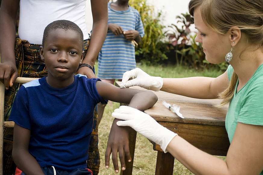 An American health worker preparing to give a African boy an injection.