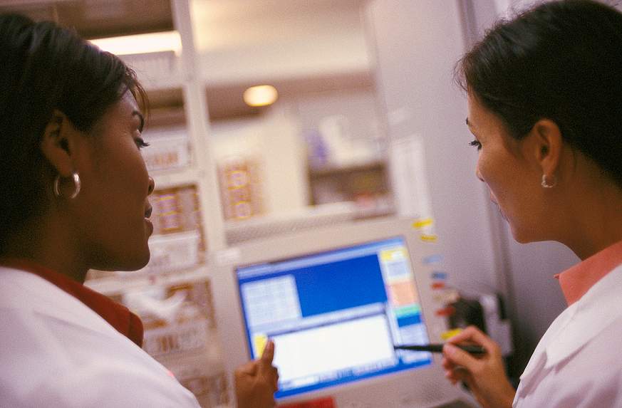 Two medical workers looking at a computer screen.