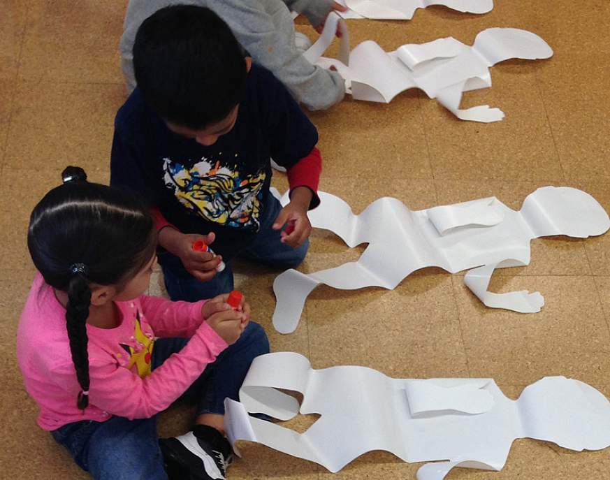 An image of children making body collages. The children will paste vegetables on the corresponding body part that benefits (such as placing two carrots on the eyes). Helps children learn the importance of eating a variety of vegetables every day for good 