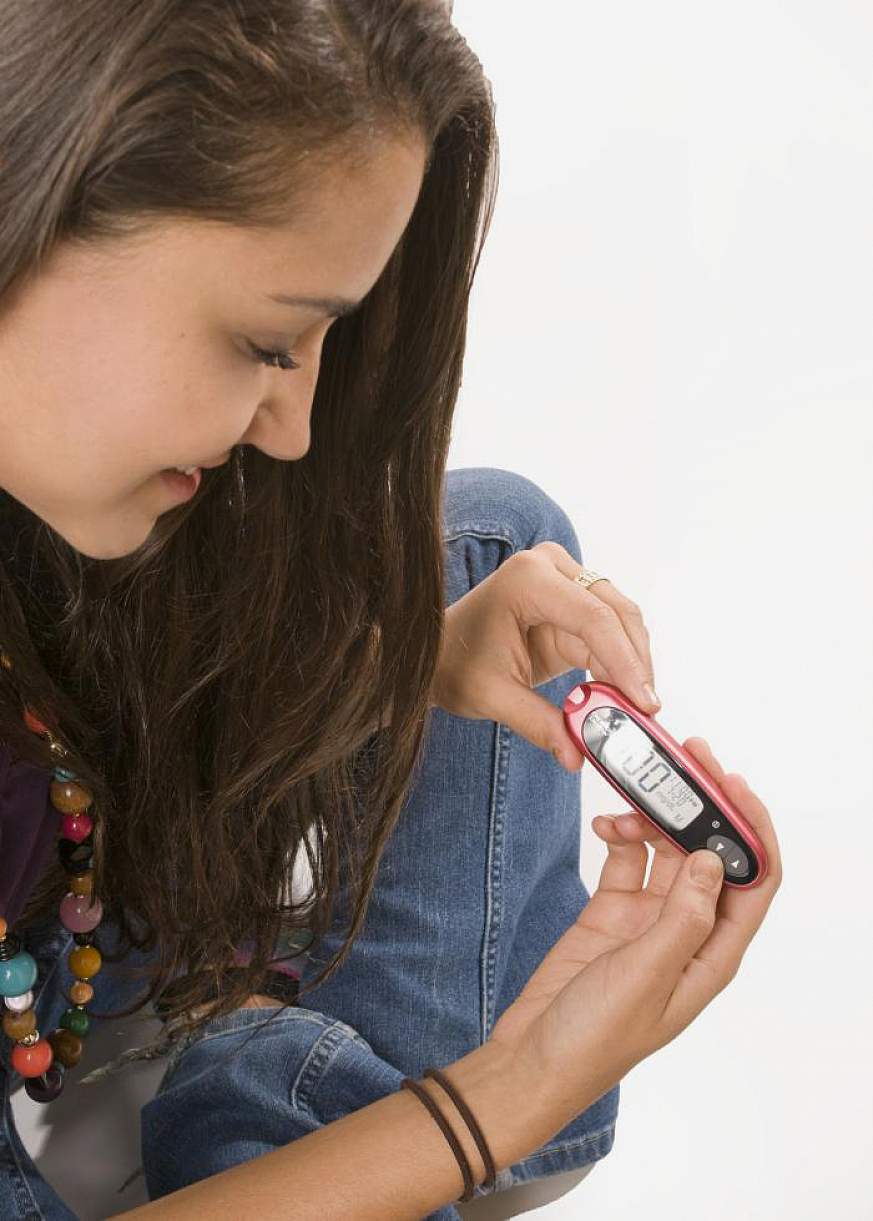 A girl with diabetes checks her blood glucose level.