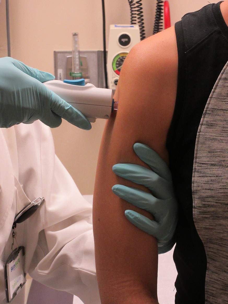 Volunteer receives needle-free vaccine in the upper arm 