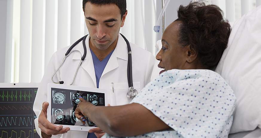 Hispanic doctor showing tablet to patient.