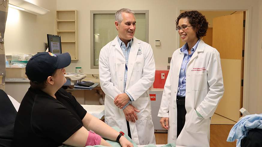 Researchers from the National Institutes of Health Kevin D. Hall, Ph.D., center, and Stephanie Chung, M.B.B.S., right, talk with a study participant at the NIH Clinical Center.