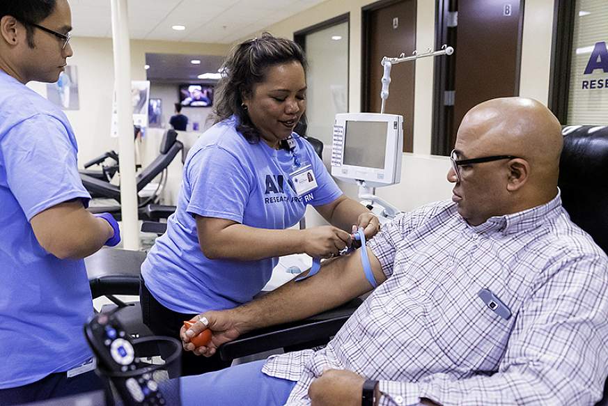 Two All of Us team members begin the process to collect a blood sample from a participant.