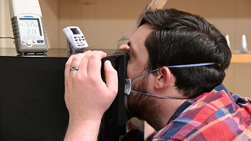 Study volunteer breathes into box while wearing mask