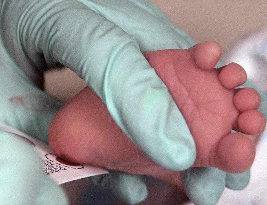 Image of a health care worker collecting an infant blood sample.