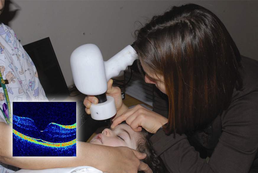 Hand-held scanning of a child's eye, with image of healthy retina (inset).