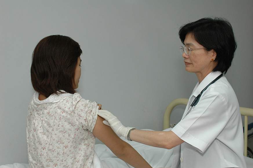 A female doctor giving an injection to a female patient.