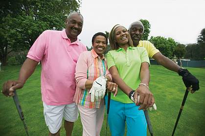 Two adult couples smile for the camera while on the golf course.