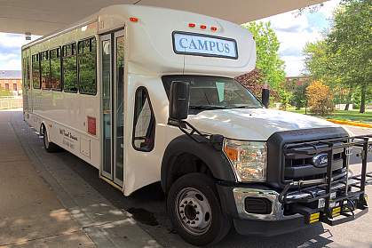 An NIH campus shuttle bus arrives at a stop.