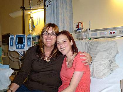 Weller and her daughter, sitting on a hospital bed, smile for the camera.