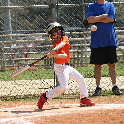 Little League batter hitting the ball.