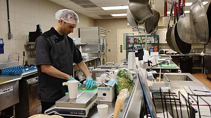 A man chops vegetables in a hospital kitchen.