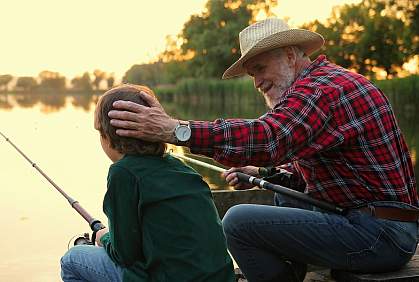 Man chatting with his grandson while fishing.
