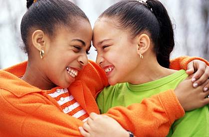 Two young African American girls smiling at each other