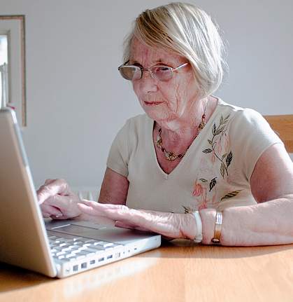 Photo of an older woman reading from her laptop