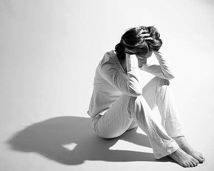 Photo of a woman sitting with her hands on her head